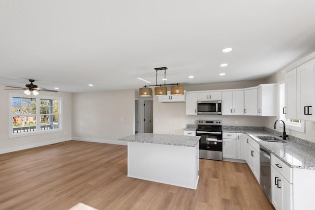 kitchen with sink, a center island, hanging light fixtures, appliances with stainless steel finishes, and white cabinets