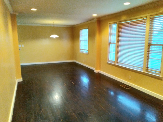 empty room with ornamental molding, dark wood-type flooring, and a healthy amount of sunlight