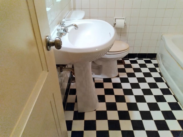 bathroom with toilet and tile walls