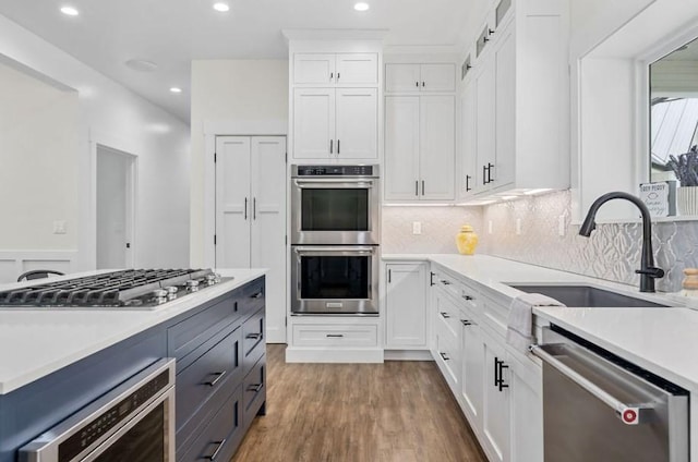 kitchen featuring decorative backsplash, stainless steel appliances, dark wood-type flooring, sink, and white cabinets