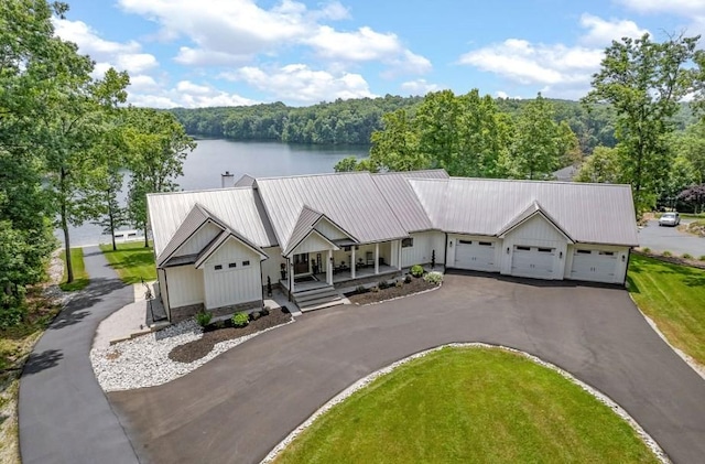 view of front facade with a front yard, covered porch, a water view, and a garage