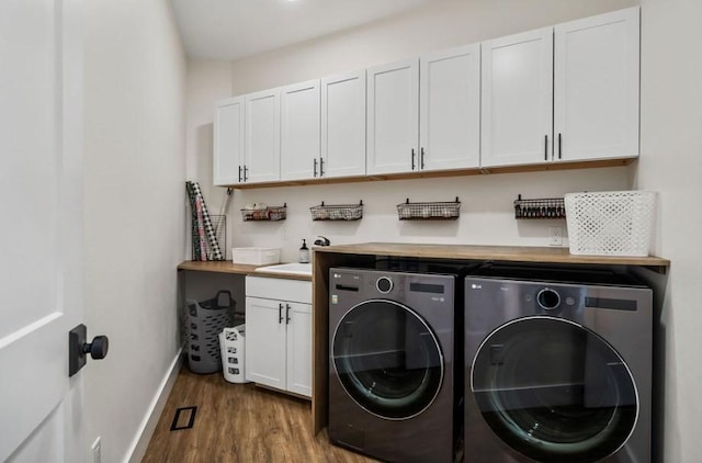 clothes washing area featuring separate washer and dryer, cabinets, and hardwood / wood-style flooring