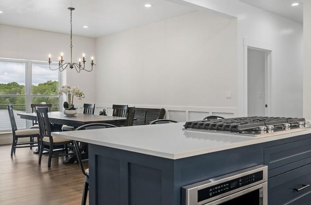 kitchen featuring pendant lighting, blue cabinets, dark hardwood / wood-style floors, a notable chandelier, and stainless steel appliances