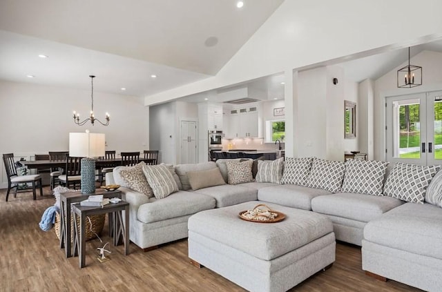 living room with a chandelier, hardwood / wood-style floors, and high vaulted ceiling