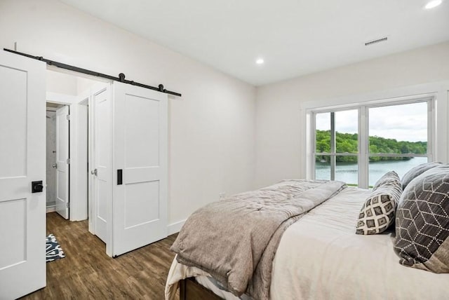 bedroom featuring access to exterior, dark hardwood / wood-style flooring, and a barn door