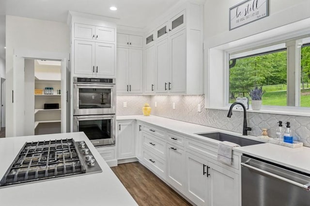 kitchen with sink, dark wood-type flooring, backsplash, white cabinets, and appliances with stainless steel finishes