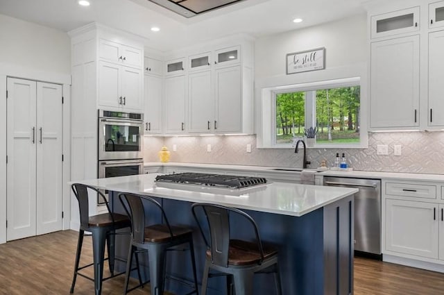 kitchen featuring a kitchen breakfast bar, a kitchen island, white cabinetry, and appliances with stainless steel finishes