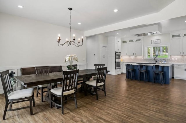 dining space featuring sink, dark wood-type flooring, and an inviting chandelier