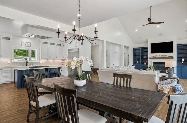 dining room featuring sink, high vaulted ceiling, dark wood-type flooring, and ceiling fan with notable chandelier