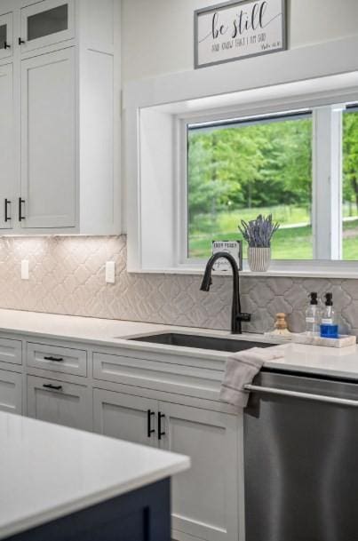 kitchen featuring a wealth of natural light, dishwasher, white cabinets, and sink