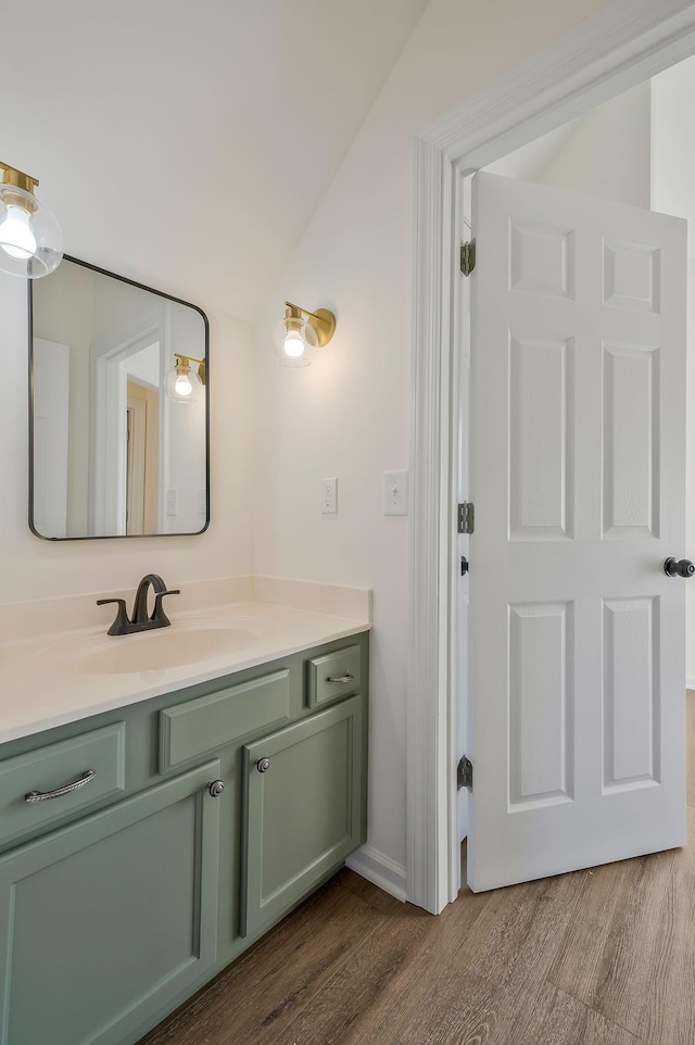 bathroom with hardwood / wood-style floors, vanity, and vaulted ceiling