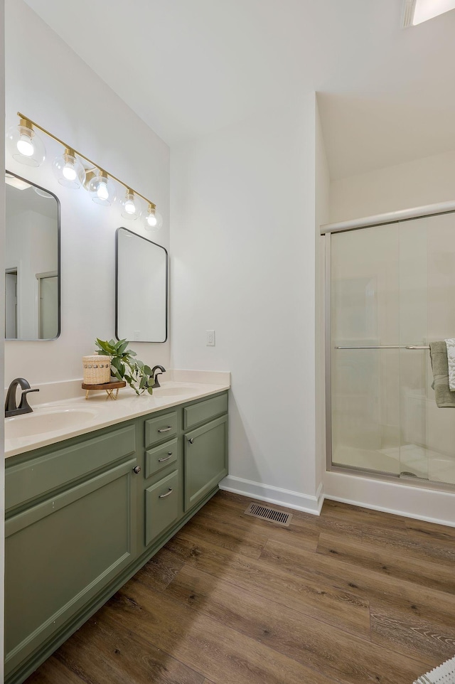 bathroom with hardwood / wood-style floors, vanity, and an enclosed shower