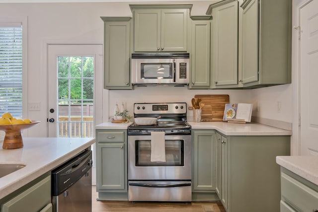 kitchen with green cabinets, stainless steel appliances, and light hardwood / wood-style floors