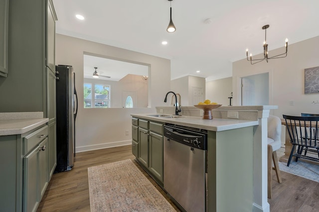 kitchen with pendant lighting, sink, appliances with stainless steel finishes, and an island with sink