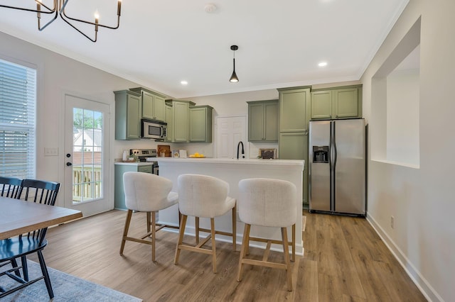 kitchen featuring appliances with stainless steel finishes, light hardwood / wood-style flooring, green cabinetry, and pendant lighting