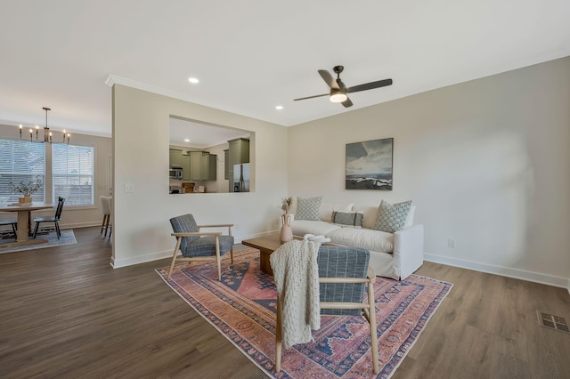 living room featuring hardwood / wood-style floors, ceiling fan with notable chandelier, and ornamental molding