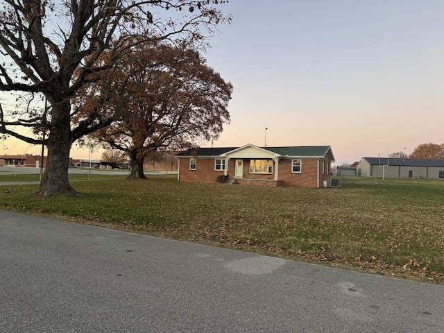 view of front of property with central air condition unit and a lawn