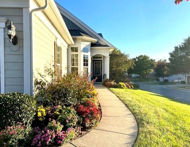 view of exterior entry featuring a water view and a lawn