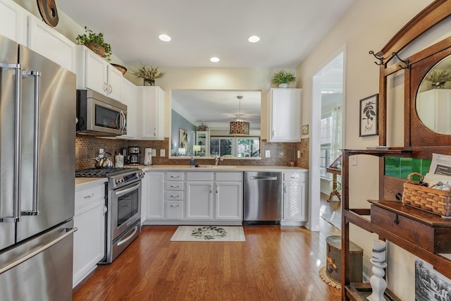 kitchen with white cabinets, wood-type flooring, decorative light fixtures, and high quality appliances