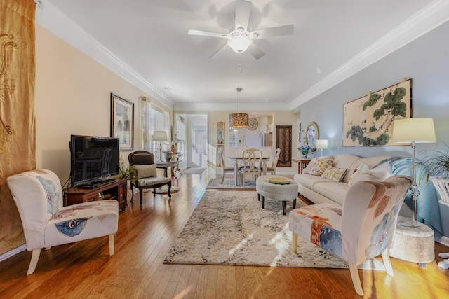 living room with light wood-type flooring, ceiling fan, and crown molding