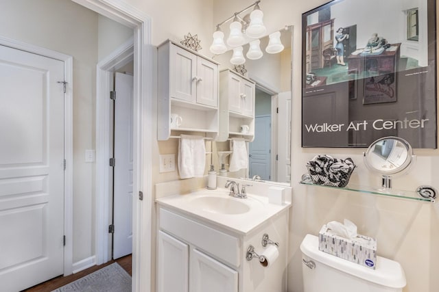 bathroom featuring hardwood / wood-style floors, vanity, a notable chandelier, and toilet