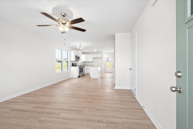 unfurnished living room with ceiling fan with notable chandelier and light hardwood / wood-style flooring