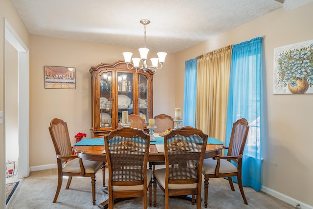 dining room featuring carpet floors, a textured ceiling, and a chandelier