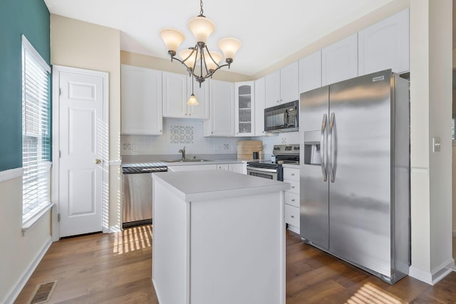 kitchen with stainless steel appliances, sink, a center island, white cabinetry, and hanging light fixtures