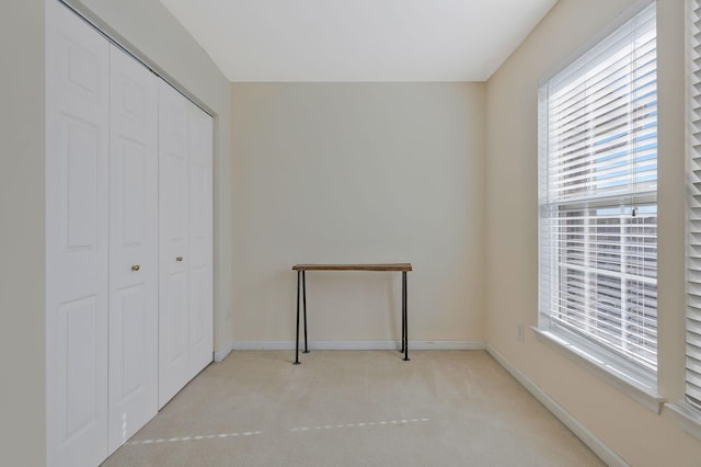 unfurnished bedroom featuring light colored carpet and a closet