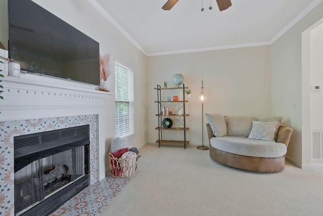 sitting room with a tiled fireplace, crown molding, ceiling fan, and light colored carpet