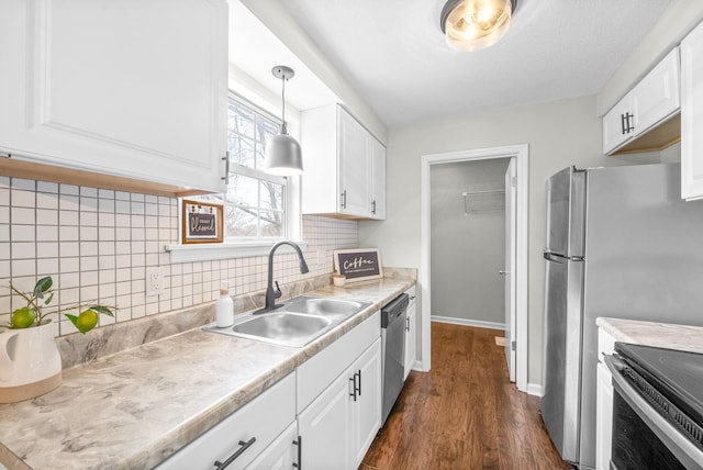 kitchen with appliances with stainless steel finishes, sink, pendant lighting, white cabinets, and dark hardwood / wood-style floors