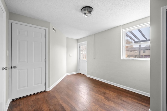 unfurnished bedroom with dark hardwood / wood-style flooring and a textured ceiling