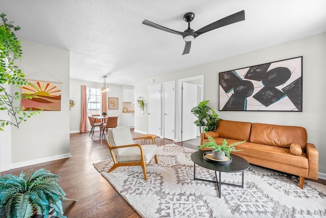 living room featuring a textured ceiling, ceiling fan with notable chandelier, and hardwood / wood-style flooring