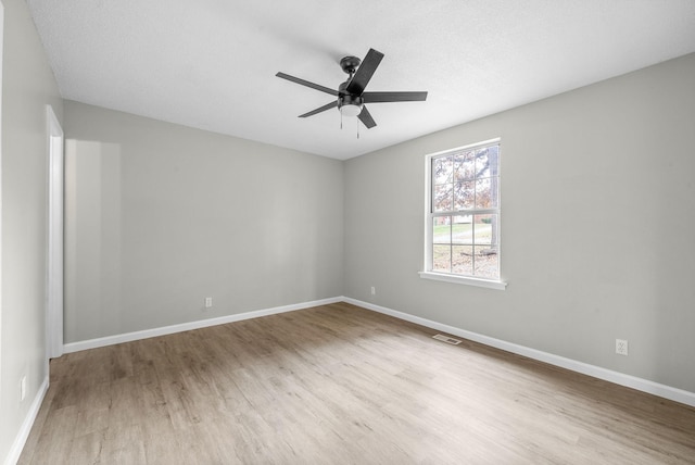 empty room with ceiling fan, light wood-type flooring, and a textured ceiling