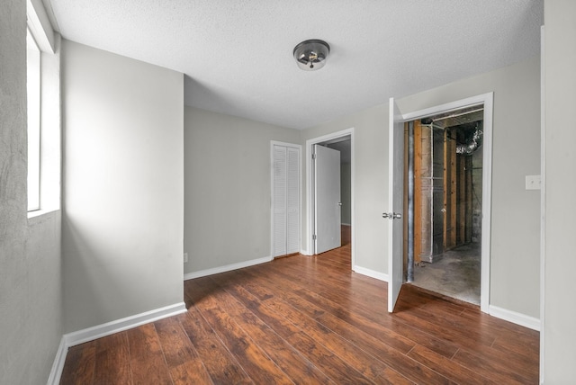 unfurnished bedroom featuring a textured ceiling, dark hardwood / wood-style floors, and a closet