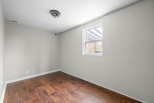 spare room featuring dark hardwood / wood-style flooring and a textured ceiling