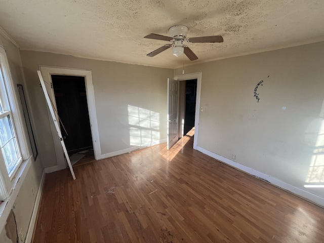 empty room with dark hardwood / wood-style floors, ceiling fan, ornamental molding, and a textured ceiling