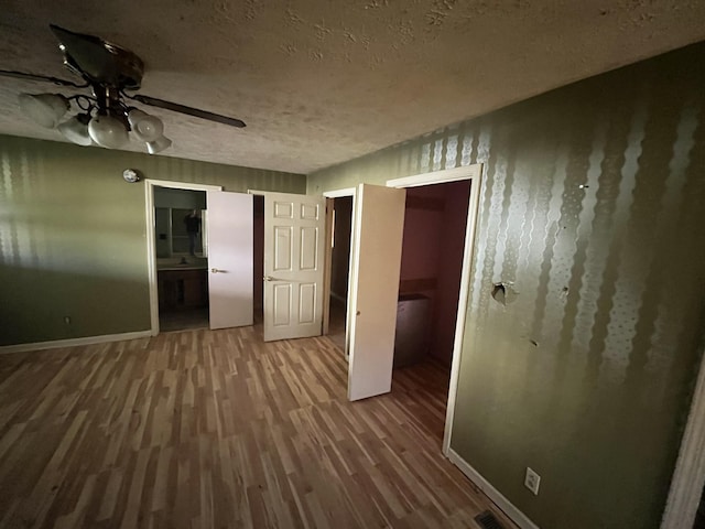 unfurnished room featuring ceiling fan, wood-type flooring, and a textured ceiling