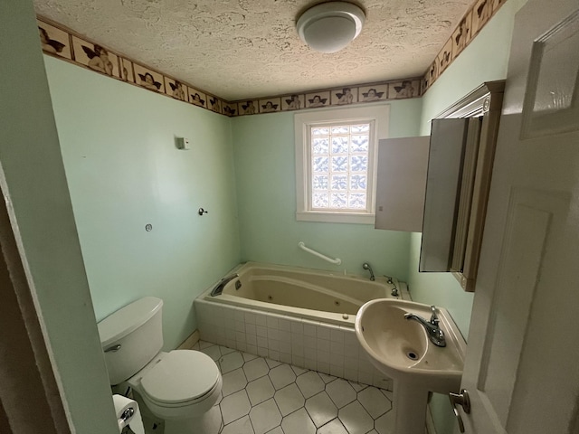 bathroom with tile patterned flooring, a relaxing tiled tub, a textured ceiling, and toilet