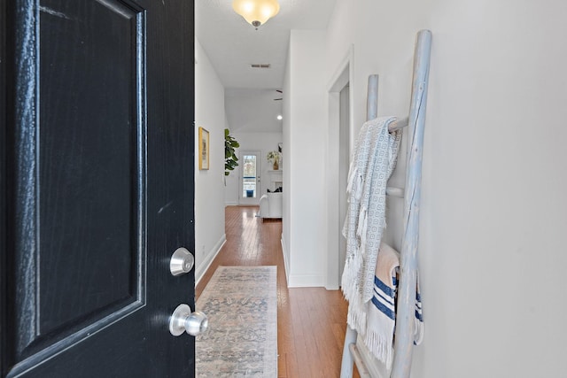 hall with hardwood / wood-style flooring, baseboards, and visible vents