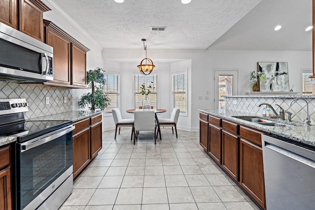 kitchen with light tile patterned floors, visible vents, appliances with stainless steel finishes, a sink, and light stone countertops