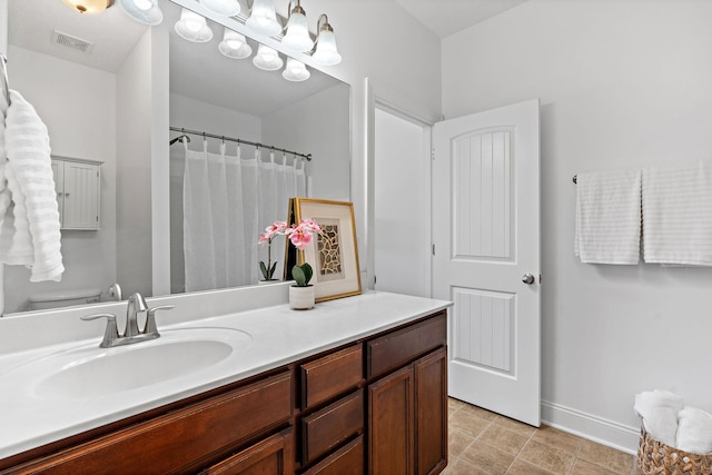 bathroom featuring visible vents, toilet, vanity, tile patterned flooring, and baseboards