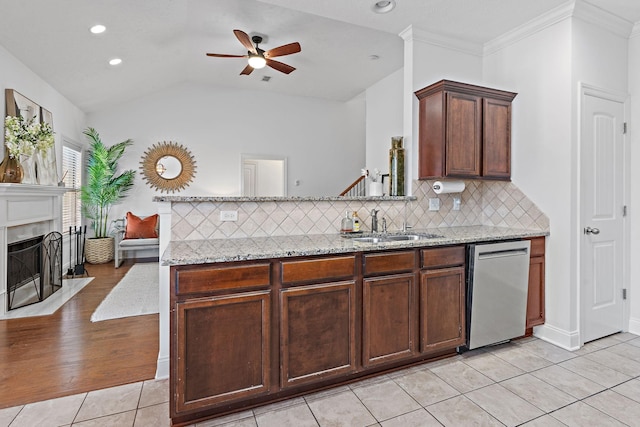 kitchen with light stone counters, a fireplace with flush hearth, light tile patterned flooring, a sink, and dishwasher