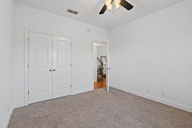 unfurnished bedroom featuring carpet floors, a ceiling fan, visible vents, baseboards, and a closet