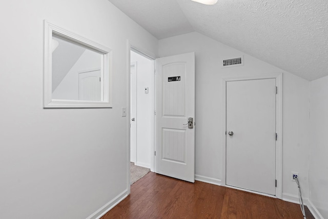 bonus room featuring lofted ceiling, visible vents, a textured ceiling, and wood finished floors