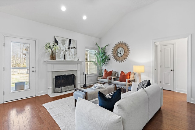 living room with baseboards, dark wood finished floors, lofted ceiling, a premium fireplace, and recessed lighting