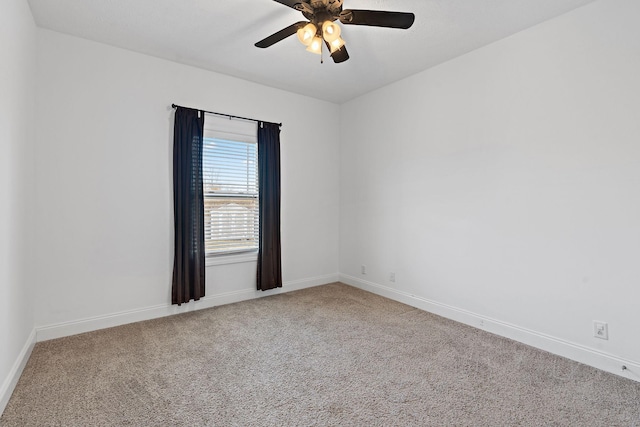 carpeted spare room featuring baseboards and a ceiling fan