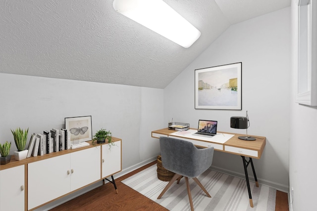 office featuring light wood-type flooring, baseboards, vaulted ceiling, and a textured ceiling