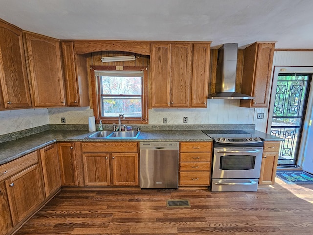 kitchen with sink, wall chimney exhaust hood, dark wood-type flooring, stainless steel appliances, and crown molding