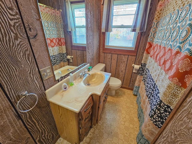 bathroom with vanity, toilet, and wood walls